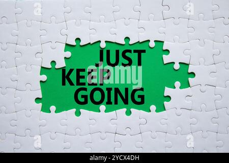 Symbole « continuez à aller ». Puzzle blanc avec des mots juste continuer. Beau fond vert. Business and Just Keep Go concept. Copier l'espace. Banque D'Images