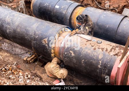 Samara, Russie - 1 octobre, 2017 : travaux de réparation du conduit de chauffage. Les travailleurs, les soudeurs faites par soudure électrique sur de gros tuyaux en fer à une profondeur d'excavat Banque D'Images