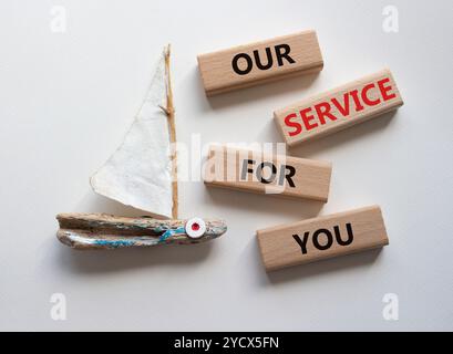 Notre service pour vous symbole. Blocs en bois avec des mots notre service pour vous. Beau fond blanc avec bateau. Affaires et notre service pour vous conce Banque D'Images