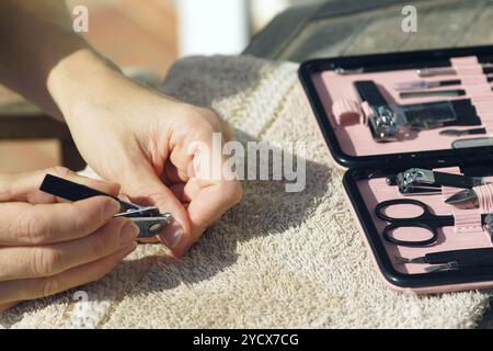 Une fille coupe la cuticule sur son pouce avec une tondeuse, gros plan. Une femme prépare ses mains pour l'application de vernis à ongles à l'aide d'outils d'un set de manucure Banque D'Images