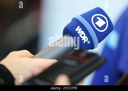 Nuremberg, Allemagne. 24 octobre 2024. Habillage des athlètes DSV (Association allemande de ski) au MesseCongressCentrum. Un journaliste tient un micro de ARD et WDR (Westdeutscher Rundfunk). Crédit : Daniel Löb/dpa/Alamy Live News Banque D'Images