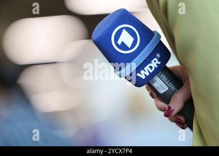 Nuremberg, Allemagne. 24 octobre 2024. Habillage des athlètes DSV (Association allemande de ski) au MesseCongressCentrum. Un journaliste tient un micro de ARD et WDR (Westdeutscher Rundfunk). Crédit : Daniel Löb/dpa/Alamy Live News Banque D'Images