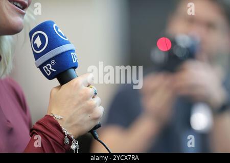 Nuremberg, Allemagne. 24 octobre 2024. Habillage des athlètes de la DSV (Association allemande de ski) dans le MesseCongressCentrum. Un athlète tient un micro de ARD et BR (Bayerischer Rundfunk). Crédit : Daniel Löb/dpa/Alamy Live News Banque D'Images