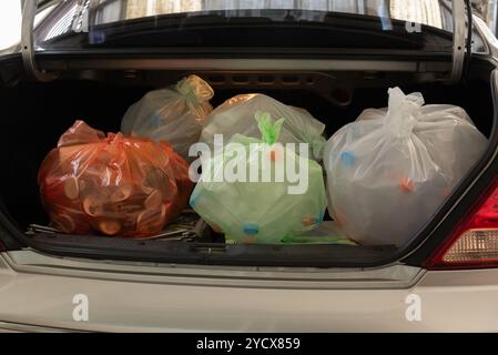 L'invention concerne un coffre de voiture rempli de sacs en plastique à code couleur contenant des matériaux recyclables tels que des bouteilles et des contenants. Banque D'Images