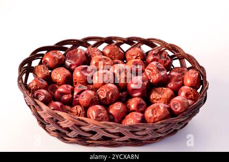 Jujujube séché fruits Ziziphus jujuba dans un petit panier en bois vue de dessus sur fond blanc Banque D'Images