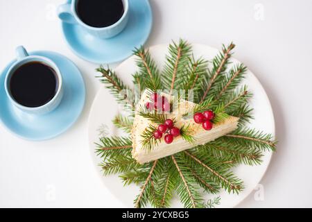 Gâteau décoré des branches d'arbre de Noël et des baies sur un fond de l'arbre de Noël et deux tasses de café Banque D'Images