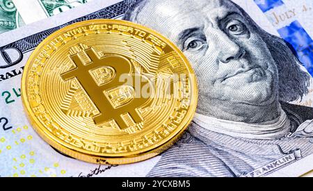 Bitcoin doré se trouvant sur un billet de cent dollars américains de gros plan Banque D'Images