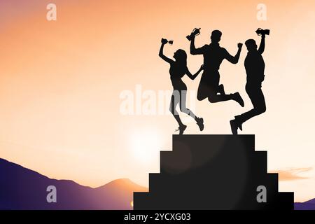Vainqueurs avec des coupes trophées sur le podium en montagne au lever du soleil Banque D'Images