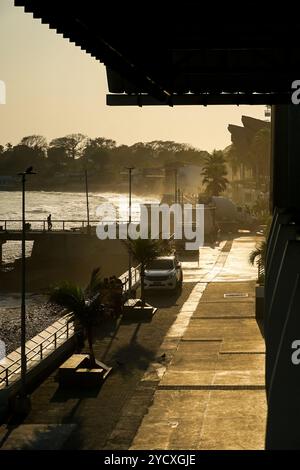 Une promenade côtière sereine au Salvador au coucher du soleil. La lumière dorée du soleil baigne la mer, la route et l'architecture environnante, mettant en évidence un s tranquille Banque D'Images