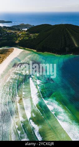 Capturée depuis un drone, cette image époustouflante met en valeur une plage immaculée de Galice, avec des eaux turquoises, des rivages de sable blanc et un vert luxuriant Banque D'Images