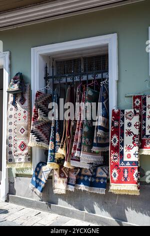 Des tapis et des textiles géorgiens traditionnels vibrants sont suspendus à l'extérieur d'une boutique pittoresque située dans le vieux Tbilissi historique, présentant des motifs complexes et riches Banque D'Images