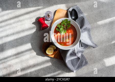 Vue de dessus de la soupe de tomates et de citrouilles de saison garnie de piment et de persil, accompagnée de tomates frites, d'un verre de vin blanc et de sel s. Banque D'Images