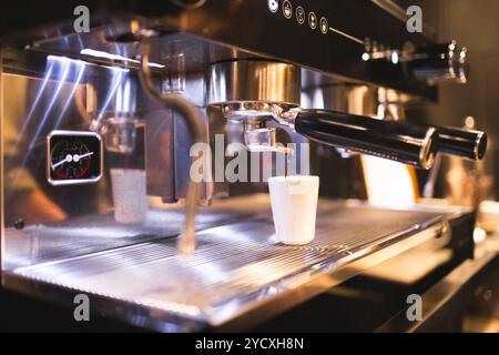 Vue rapprochée d'une machine espresso professionnelle préparant du café frais, avec montée de vapeur et remplissage d'une tasse blanche Banque D'Images