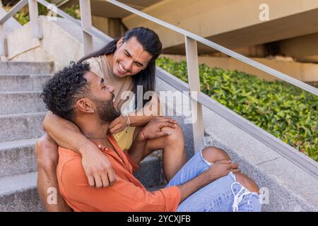 Un couple gay aimant partage un moment joyeux sur les escaliers de la ville, montrant leur affection les deux individus semblent avoir une AM multiethnique latine et africaine Banque D'Images