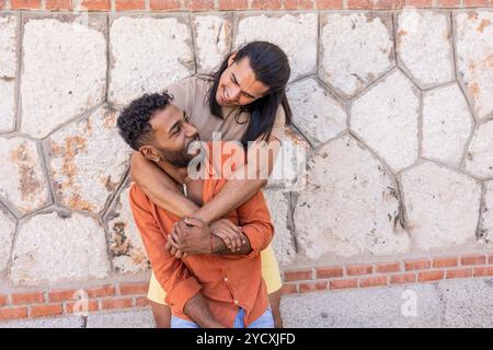 Un couple gay aimant, reflétant un mélange d'héritage américain latino-américain et afro-américain, partage un moment joyeux dans un contexte urbain leurs happines Banque D'Images