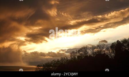 Un coucher de soleil nuageux évoquant la silhouette du paysage lausannois, mettant en valeur la beauté tranquille du ciel suisse. Banque D'Images