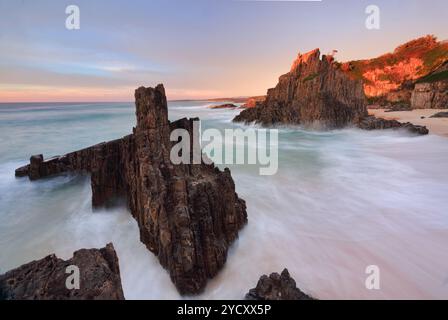 L'océan coule autour des piles volcaniques de la mer alors que la première lumière frappe le paysage Banque D'Images