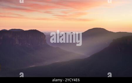 Montagnes bleues et ciel rouge de l'aube Banque D'Images