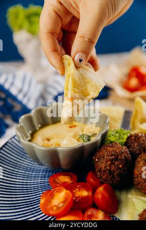 Tremper à la main le pain pita dans le houmous crémeux. Expérience de collation parfaite au moyen-Orient Banque D'Images