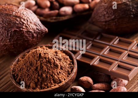 Barre de chocolat, bonbon sucré, les fèves de cacao et poudre sur fond de bois Banque D'Images