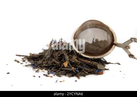 Feuilles de thé séchées et cuillère à infuser sur fond blanc. Banque D'Images