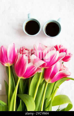 Deux tasses de café et un bouquet de tulipes roses Banque D'Images