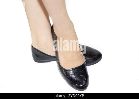 Ballerines noires sur les jambes féminines sur un fond blanc. Chaussures d'été pour femme. Chaussures de ballet noir d'affaires sur un backgro blanc Banque D'Images