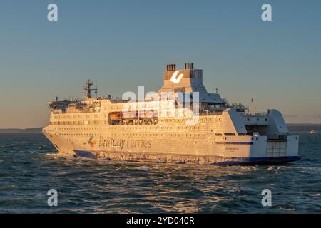 Le Brittany ferries navire MV Normandie quitte Portsmouth avec le soleil tôt le matin se reflétant sur le côté des navires. Banque D'Images