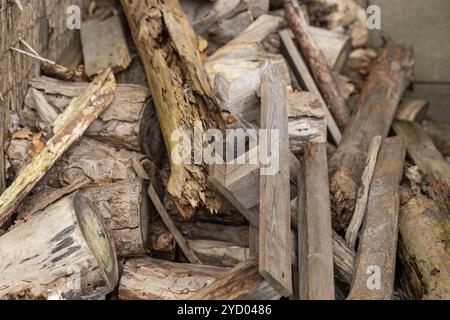 Pile de bûches et de planches de bois vieilles et altérées empilées à l'extérieur dans un environnement rustique Banque D'Images