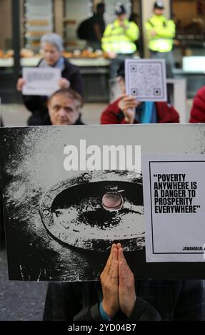 Londres, Angleterre, Royaume-Uni. 24 octobre 2024. Pendant la manifestation, un manifestant jette un coup d'œil à une pancarte avec des mains de prière et une pancarte avec une citation de Nehru disant˜la pauvreté partout est Un danger pour la prospérité partout'. Des manifestants brandissent des signes de prisonniers politiques emprisonnés devant le ministère de la Justice à Londres. Les manifestants se rassemblent devant le bureau du procureur général en silence et tiennent des pancartes de soutien aux prisonniers politiques. Les photographies du prisonnier apparaissent sur les pancartes. Les manifestants soulignent le fait que, sur instruction des juges, de nombreux militants emprisonnés ont été una Banque D'Images