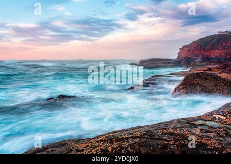 Debout sur le bord de la plate-forme rocheuse côtière regardant les vagues se briser upong la côte rocheuse Banque D'Images