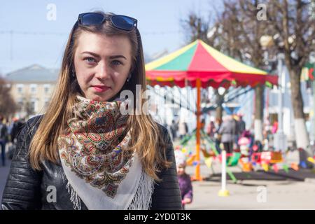 La jeune fille aux cheveux blonds promenades autour de la ville au printemps. Une fille aux cheveux blonds. Jeune fille belle et mince Banque D'Images