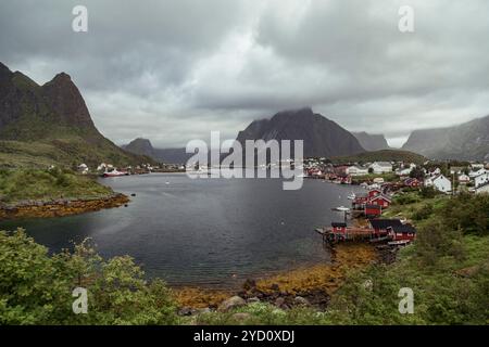 Reine dans les îles Lofoten offre une vue imprenable avec des bateaux de pêche flottant dans les eaux tranquilles, entouré de montagnes imposantes et spectaculaire Banque D'Images