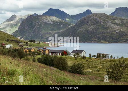 Découvrez le paysage époustouflant des îles Lofoten, où les villages pittoresques bordent un lac serein, entourés de montagnes majestueuses et d'une végétation luxuriante Banque D'Images