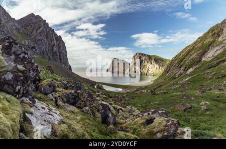 Explorez le magnifique terrain glaciaire de Fredvang dans les îles Lofoten, où les falaises escarpées s'élèvent au-dessus d'une baie tranquille, invitant à l'aventure et à la randonnée Banque D'Images