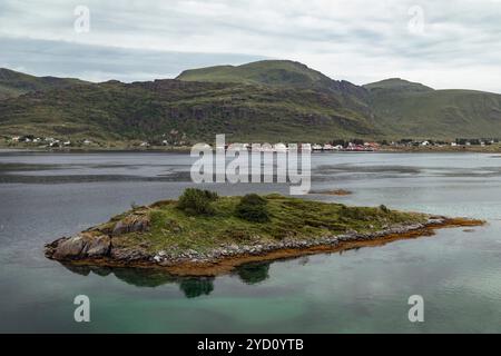 Une île tranquille repose dans les eaux calmes d'une baie dans les îles Lofoten pendant les heures de soirée, entourée de douces collines et d'un village pittoresque Banque D'Images