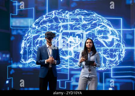 Portrait de spécialistes faisant une démonstration de réalité virtuelle lors d’une convention d’IA rassemblant des startups technologiques. Ingénieurs à l'événement du sommet montrant comment utiliser les lunettes VR et la technologie de l'intelligence artificielle Banque D'Images