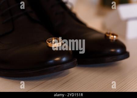 Anneaux de mariage élégants reposant sur des chaussures noires classiques. Banque D'Images