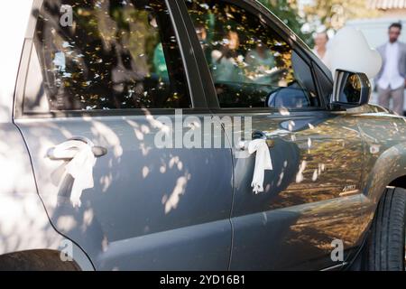 Élégante voiture de mariage avec des rubans décoratifs et un environnement ensoleillé. Banque D'Images