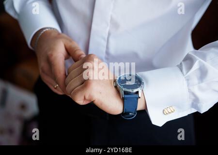 Homme élégant ajustant sa montre dans une chemise de robe blanche classique. Banque D'Images