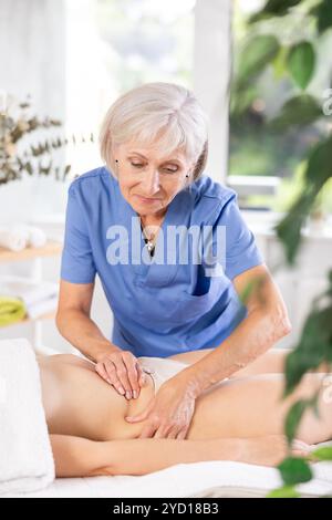 Masseuse mature qualifiée faisant des côtés anti-cellulite et massage du ventre à la femme Banque D'Images
