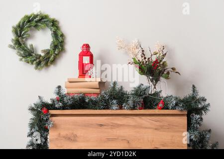 Lanterne avec bougie allumée et décor de Noël sur la table près du mur blanc à la maison Banque D'Images