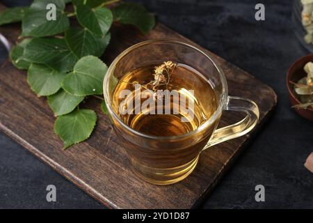 Tasse de thé de tilleul savoureux avec des feuilles sur fond noir Banque D'Images