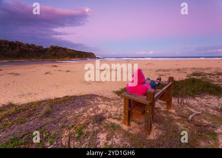 Femme se détend sur le banc donnant sur la plage dans l'après-midi crépuscule Banque D'Images