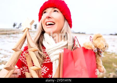 Femme joyeuse tenant un petit arbre de Noël en bois et des sacs-cadeaux Banque D'Images