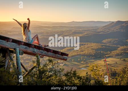 Femme aimant la liberté se sentant exaltée sur la rampe haut au-dessus de la vallée Banque D'Images