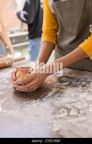 Temps de Noël, femme pétrissant la pâte sur la surface farinée à la cuisine à la maison Banque D'Images