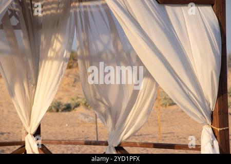 Gazebo sur la plage au bord de la mer. Plage de sable. Les rideaux se développent dans le vent. Banque D'Images