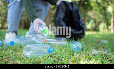 Femme de bénévoles dévoués participent à une activité de nettoyage environnemental dans un parc. Femme portant des gants et tenant de grands sacs noirs. Femme Banque D'Images