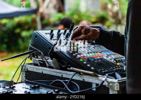 Une vue rapprochée sur la main d'un disc-jockey alors qu'il actionne les boutons d'un mixeur de musique moderne pendant un festival de musique Banque D'Images